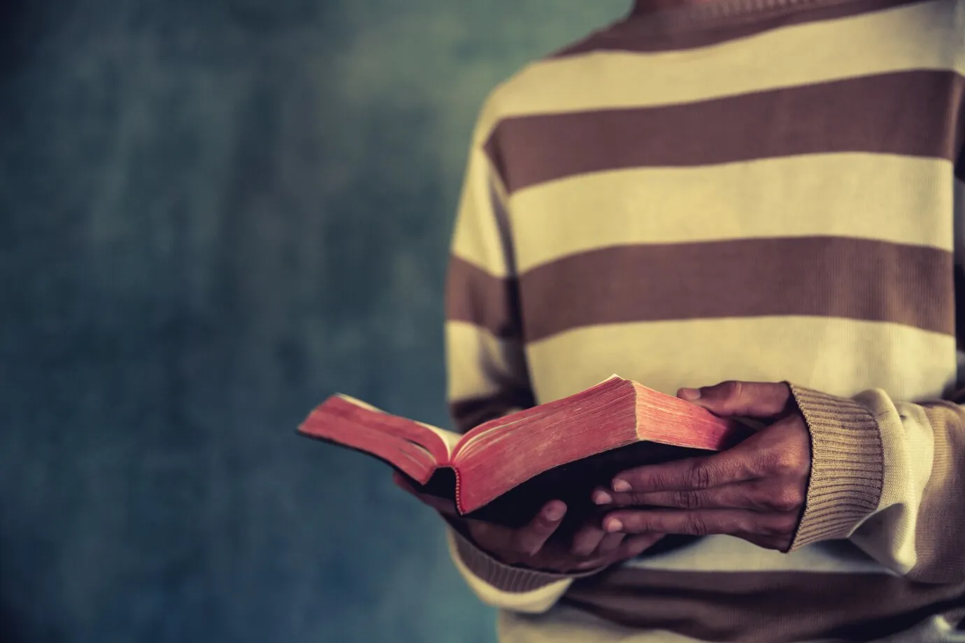 Man standing while reading the Bible